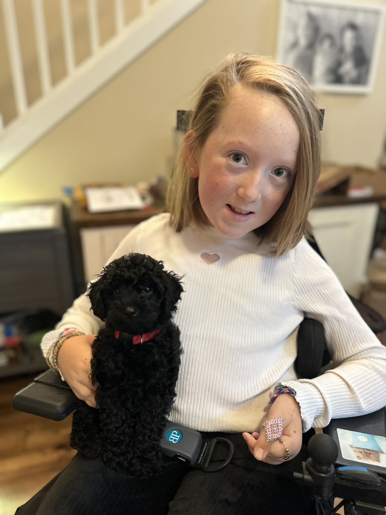 Bella holding a tiny black puppy